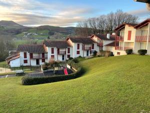 a group of houses on a hill with a green field at HOSTA Piscine Vue Montagnes in Souraïde