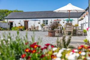 a cottage with an umbrella and chairs and flowers at East Trewent Farm in Pembroke
