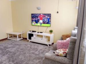 a living room with a couch and a tv on the wall at Greenvale's 2 Bedroom in Eldoret