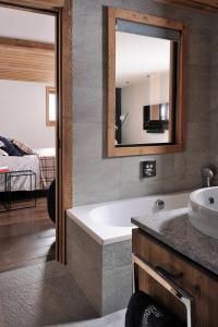 a bathroom with a tub and a sink and a mirror at Chalet Le Moulin, Courchevel Le Praz, 6 chambres, Ski in, Ski out in Courchevel