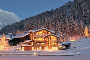 a large log house in the snow at night at Chalet Le Moulin, Courchevel Le Praz, 6 chambres, Ski in, Ski out in Courchevel