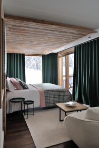 una camera da letto con un grande letto con tende verdi di Chalet Le Moulin, Courchevel Le Praz, 6 chambres, Ski in, Ski out a Courchevel