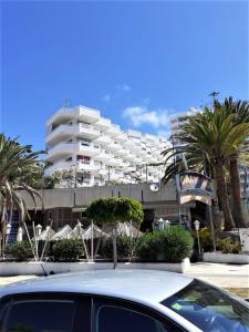 a car parked in front of a building with palm trees at Studio Ponderosa in Playa de las Americas