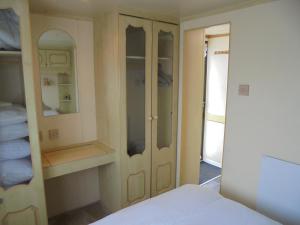 a room with a bed and a closet with a mirror at 7 Berth on Coral Beach Granada II in Ingoldmells