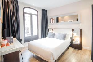 a bedroom with a white bed and a window at Petit Palace Chueca in Madrid