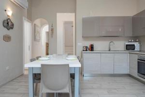 a kitchen with a white table with chairs in it at Bellissimo appartamento con veranda privata al centro di Porto Rotondo in Porto Rotondo