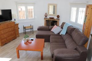 ein Wohnzimmer mit einem braunen Sofa und einem Tisch in der Unterkunft CHALET CON PISCINA PRIVADA in Torrevieja