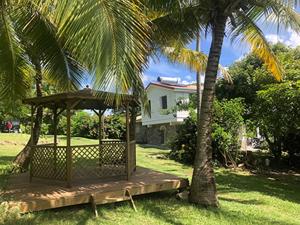 un palmier avec un kiosque à côté d'une maison dans l'établissement La Sucrerie, magnifique villa avec Piscine, à Sainte-Anne