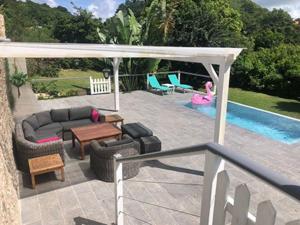 une terrasse avec un canapé, une table et une piscine dans l'établissement La Sucrerie, magnifique villa avec Piscine, à Sainte-Anne
