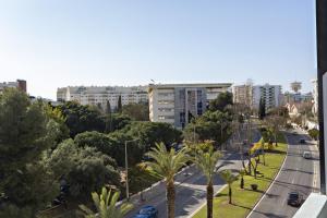 uma rua da cidade com palmeiras e edifícios em Apartamento Gulbenkian em Faro