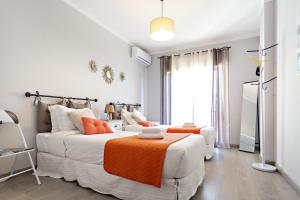 uma sala de estar com um sofá branco e um cobertor laranja em Apartamento Gulbenkian em Faro