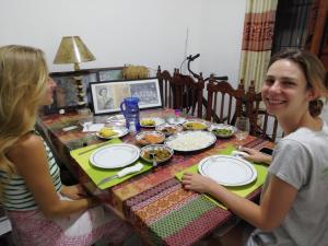 Zwei Mädchen sitzen an einem Tisch mit Teller Essen in der Unterkunft BAS Balcony in Anuradhapura