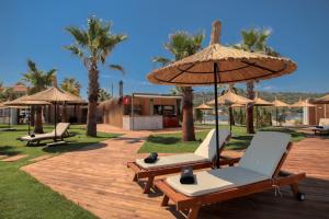 una terraza con 2 tumbonas y una sombrilla en Anda Beach Bistro & Rooms en Cunda