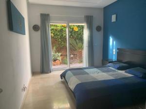 Dormitorio azul con cama y ventana en Chalet Mirleft en Mirleft