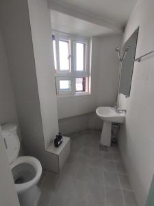a white bathroom with a toilet and a sink at Joy Guesthouse in Seoul