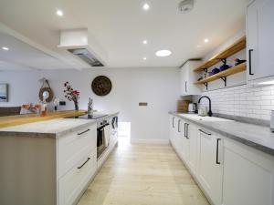 une cuisine avec des armoires blanches et un plancher en bois dans l'établissement Joinery Cottage, à Porthleven