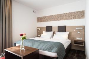 une chambre d'hôtel avec un lit et un vase de fleurs sur une table dans l'établissement Hotel Drei Rosen, à Moosburg an der Isar