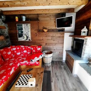 a living room with a red couch and a fireplace at Baita Il Focolare - Your Mountain Holiday in Premana