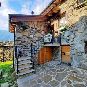 a stone building with a staircase and a balcony at Baita Il Focolare - Your Mountain Holiday in Premana