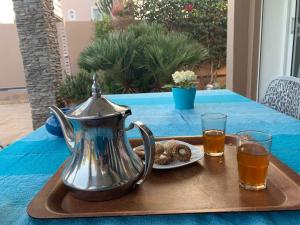 a tray with a tea kettle and cookies on a table at Chalet Mirleft in Mirleft