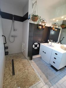ein Badezimmer mit einem weißen Waschbecken und einer Dusche in der Unterkunft Au numéro Cinq in Donville-les-Bains