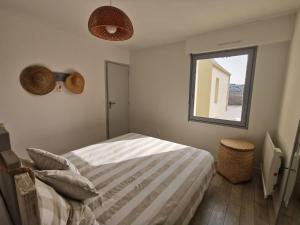 Schlafzimmer mit einem Bett und einem Fenster in der Unterkunft Au numéro Cinq in Donville-les-Bains