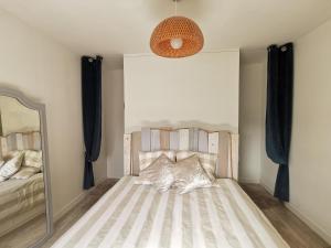 een slaapkamer met een bed met een spiegel en een spiegel bij Au numéro Cinq in Donville-les-Bains