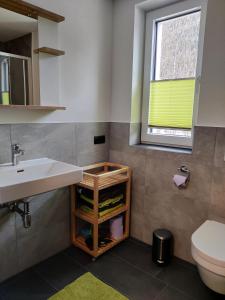 a bathroom with a sink and a toilet and a window at Apartment am Mühlbach in Reith bei Seefeld