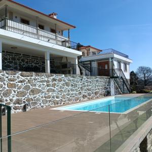 une maison avec une piscine à côté d'un mur en pierre dans l'établissement Casa do Laranjal, 