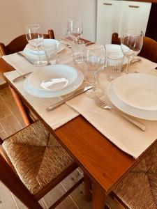 a wooden table with plates and wine glasses on it at Agricampeggio La Piaggia - Agriturismo in Piombino
