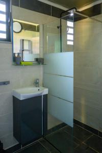 La salle de bains est pourvue d'un lavabo et d'une douche en verre. dans l'établissement Les bungalows meublés du Pharest, à Sainte-Suzanne