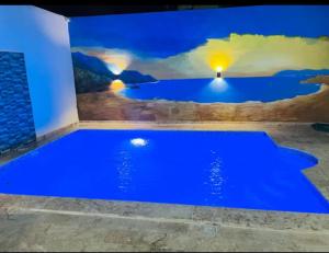 una piscina blu in una stanza con un dipinto sul muro di RG Sol 1 a Pantoja