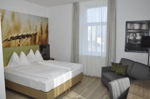 ein Hotelzimmer mit einem Bett und einem Stuhl in der Unterkunft Brauhaus Falkenstein in Lienz