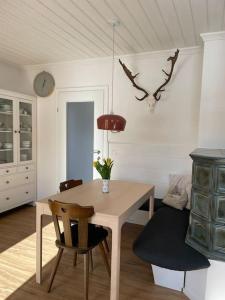 a dining room with a table and chairs and a clock at Das Fenster zum See-Weissensee in Weissensee