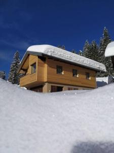 a house covered in snow in front of it at Das Fenster zum See-Weissensee in Weissensee