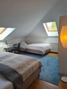 a bedroom with two beds and a desk and two windows at Willa Tini Sauna Basen in Gościno