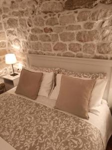 a bed in a room with a brick wall at Room Ivana in Rab