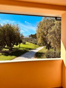 a window with a view of a dirt road at Agricampeggio La Piaggia - Agriturismo in Piombino