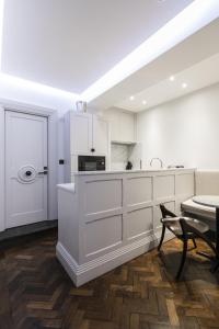 a white kitchen with white cabinets and a table at The Marlborough Suite in London