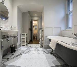 a white bathroom with a tub and a sink at The Marlborough Suite in London
