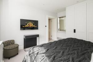 a bedroom with a bed and a tv and a chair at The Connaught Suite in London