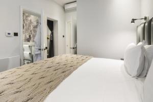 een witte slaapkamer met een groot bed met witte kussens bij The Connaught Suite in Londen