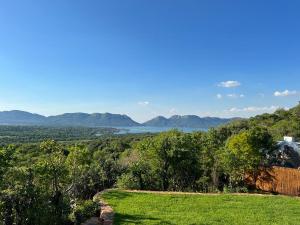 a field with a view of the water and mountains at JUMANJI NATURE RESORT in Hartbeespoort