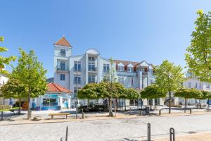 um grande edifício branco com árvores em frente em Strandjuwel 251 em Kühlungsborn