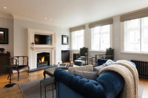 a living room with a blue couch and a fireplace at The Grosvenor Square Penthouse in London
