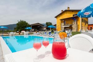 two wine glasses sitting on a table next to a swimming pool at Le Murette appartamenti in Affi