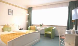 Schlafzimmer mit einem Bett, einem Tisch und einem Fenster in der Unterkunft Hotel Diekseequell Superior am Dieksee in Malente