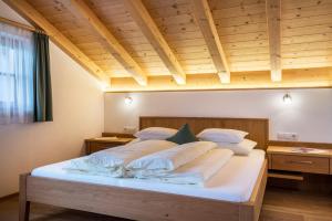 Una cama grande en una habitación con techo de madera. en Feldererhof Apt Dolomitenblick, en Santa Maddalena in Casies