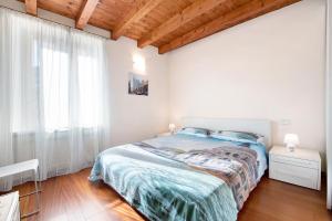 a white bedroom with a bed and a window at Casa Grazia - Appartamento Luce in Gargnano