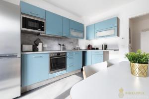 een keuken met blauwe kasten en een witte tafel bij Pineapple Apartments Dresden Zwinger IV - 65 qm - 1x free parking in Dresden